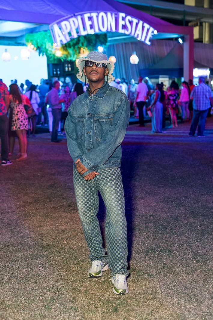 Social media influencer, podcaster and content, creator Rushane ‘RushCam’ Campbell dons a denim jacket and checkered jeans.
