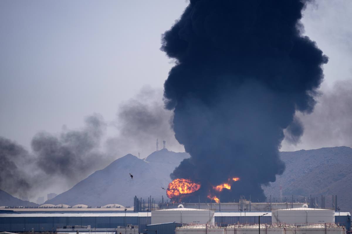 A fire and plume of smoke rise after, according to authorities. debris from an intercepted Iranian drone struck an oil facility in Fujairah, United Arab Emirates on March 14, 2026.(AP Photo/Altaf Qadri)