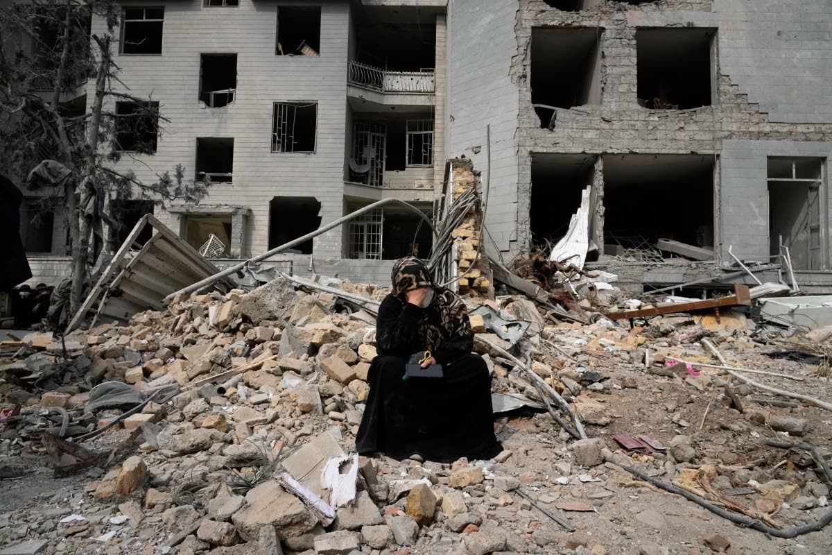
A woman sits on rubble across from a residential building damaged last Sunday during the US-Israeli air campaign in Tehran, Iran, Thursday, March 12, 2026.