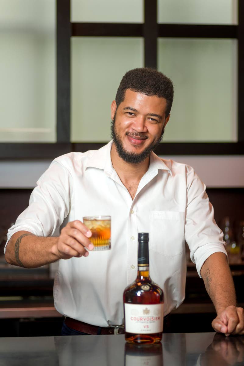 Mixologist Sheldon Spencer holding a glass of Courvoisier with ginger ale.