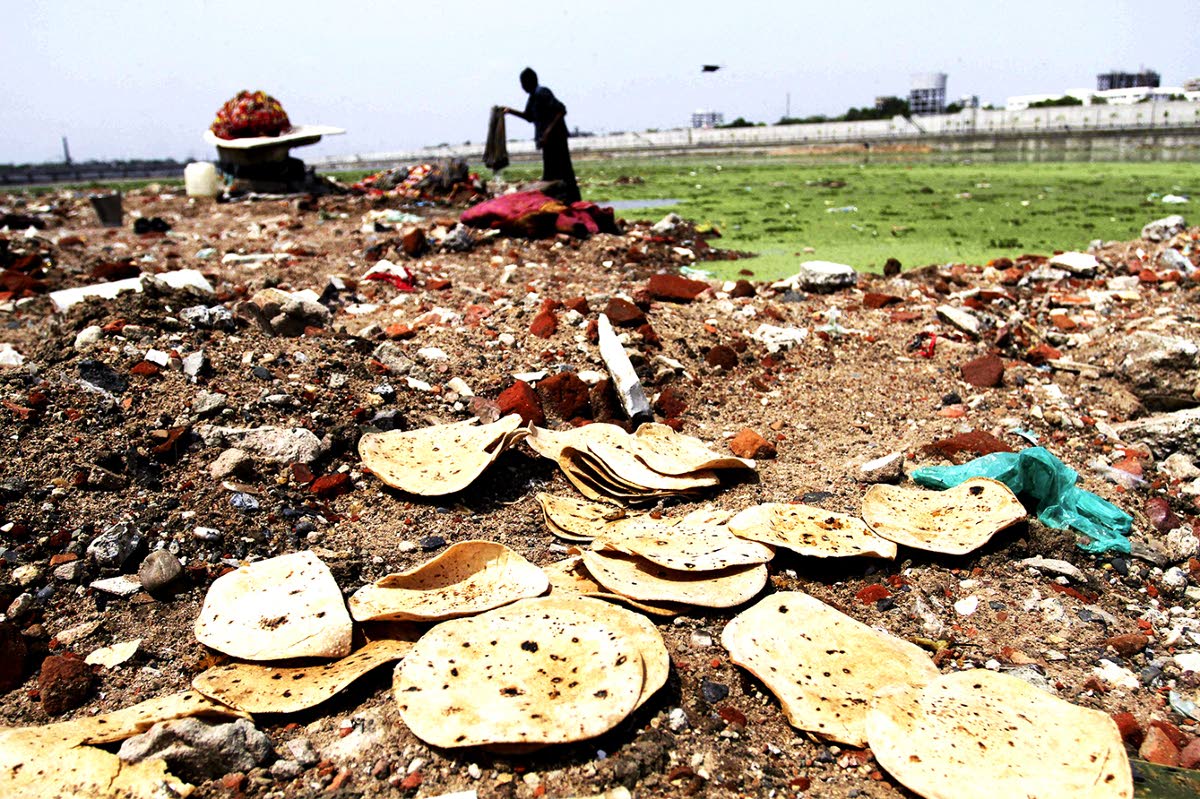 This June 5, 2013 file photo shows discarded rotis, or Indian bread, along the river bank as an Indian man cleans clothes in the polluted Sabarmati River in Ahmadabad, India. In a United Nations Food and Agricultural Organization report released Wednesday,