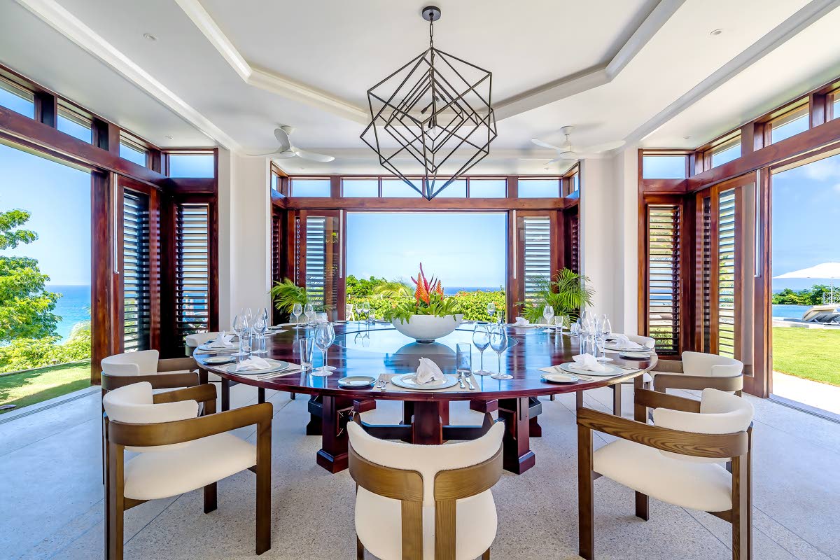 The dining room completely opens to greenery and the sea beyond.