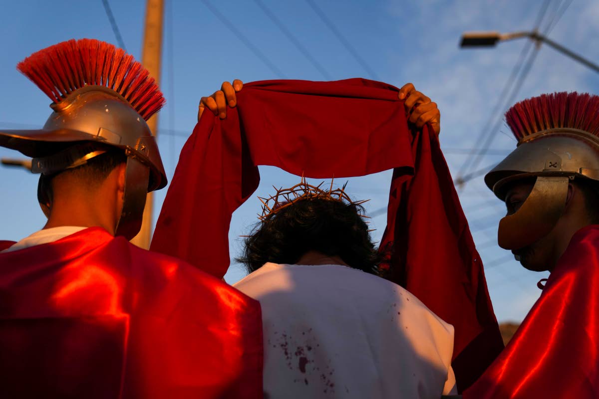 Roman soldiers dress David Sanchez, playing the role of Jesus Christ, with a crown and scarlet cloak to mock his claim as “King of the Jews”, during a Way of the Cross reenactment as part of Holy Week celebrations, in Colina, Chile.