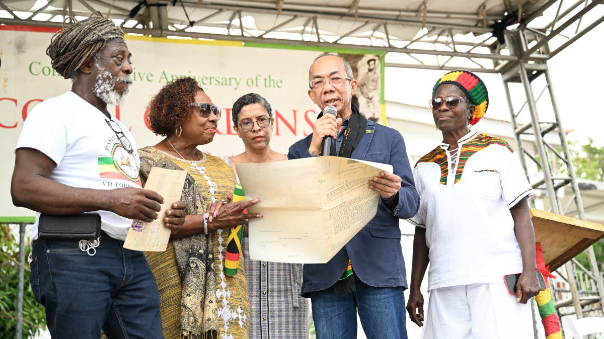 Deputy Prime Minister and Minister of National Security, Dr Horace Chang (second right), and Minister of Culture, Gender, Entertainment and Sport, Olivia Grange (second left), examine certificates of title for lands transferred to the Rastafari Coral Gard