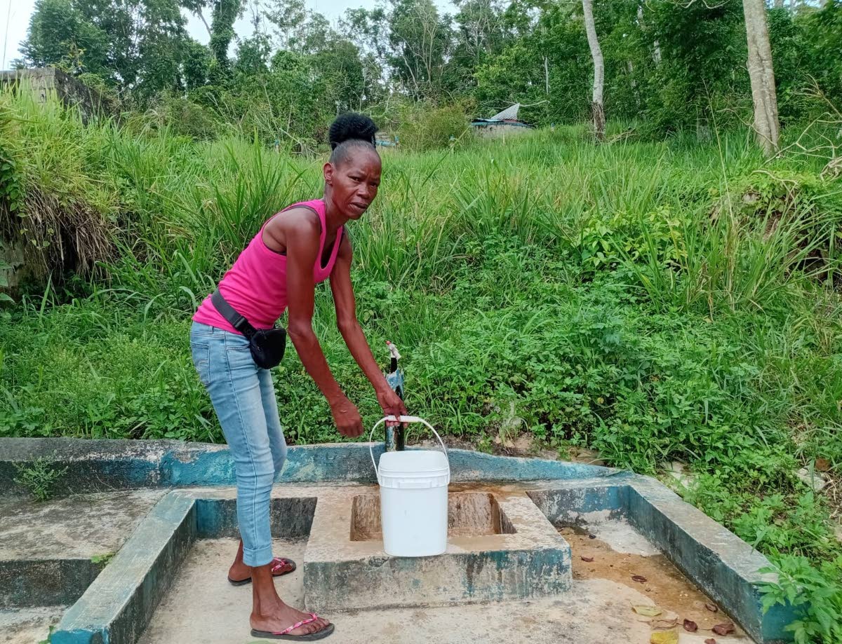 A resident of Beecher Town, St Ann, collects water from a community standpipe.