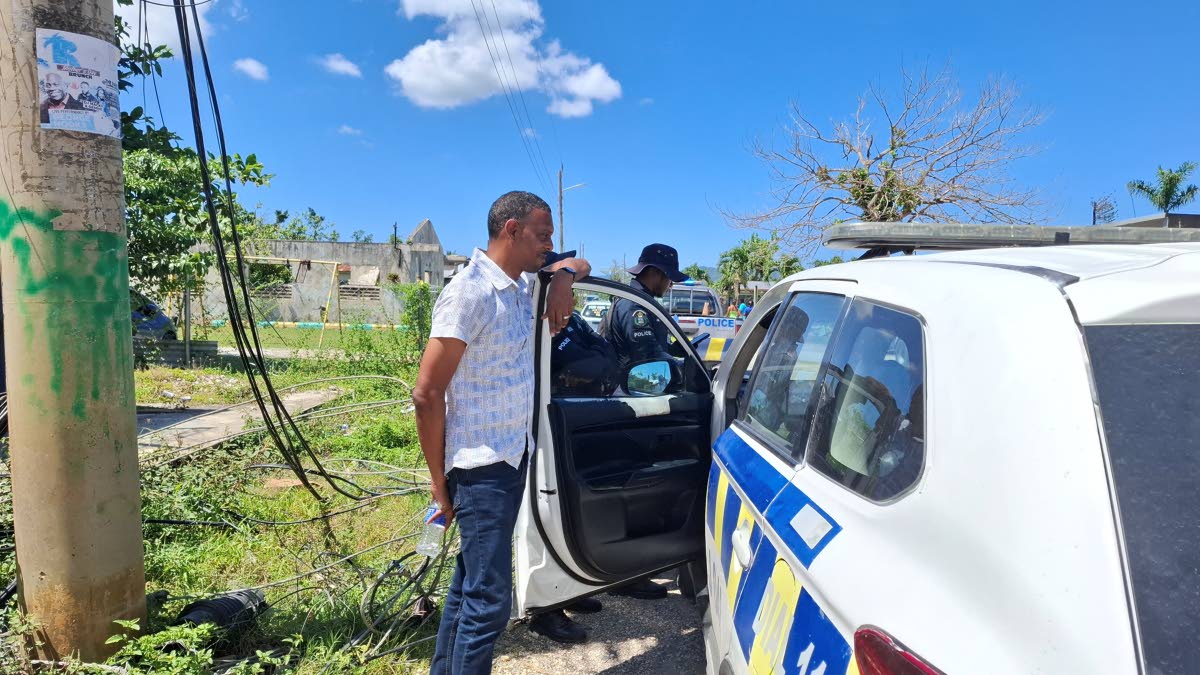 Member of Parliament Dwayne Vaz speaks with members of the Jamaica Constabulary Force after addressing residents in Hertford amid ongoing concerns about road conditions.