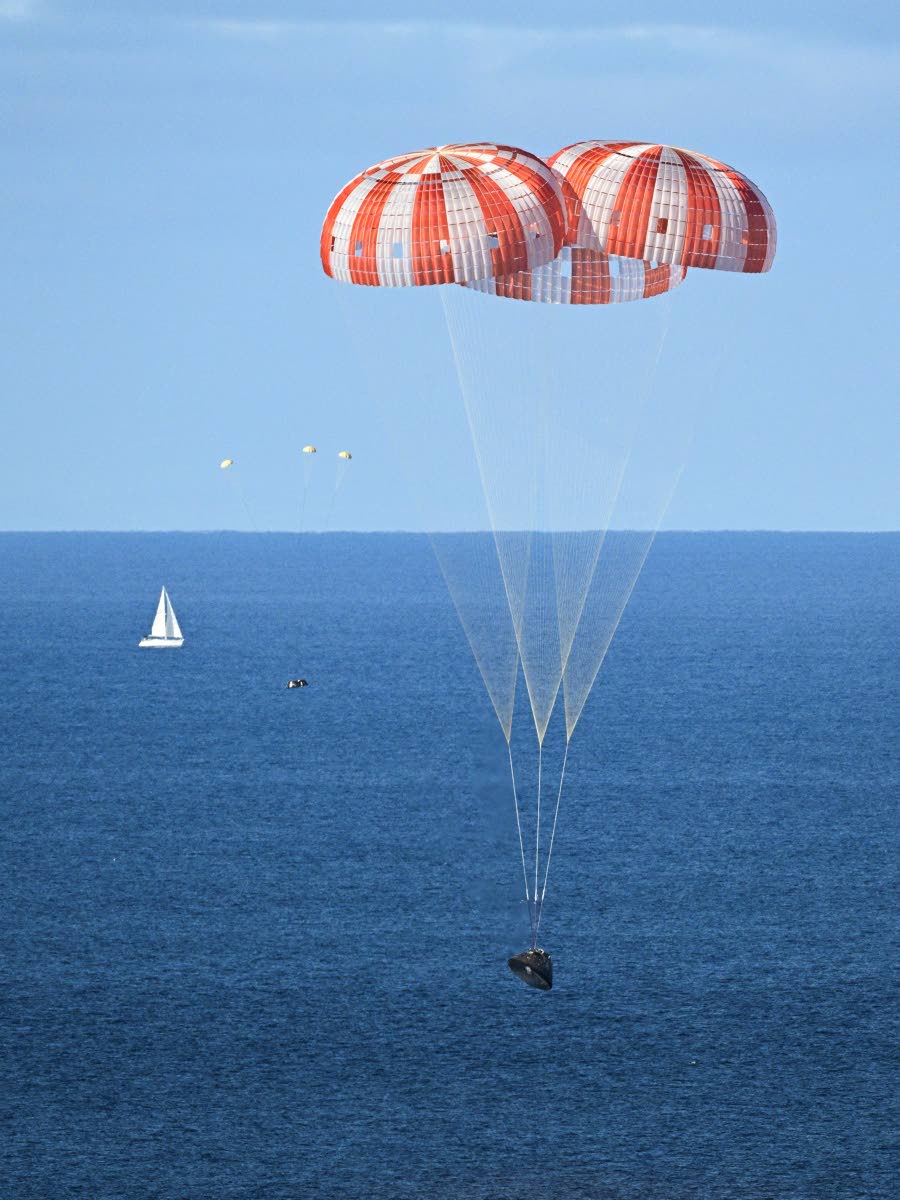 In this photo provided by NASA, NASA’s Orion capsule descends under its main parachutes over the Pacific Ocean off the coast of California, following the Artemis II mission on Friday, April 10, 2026.
