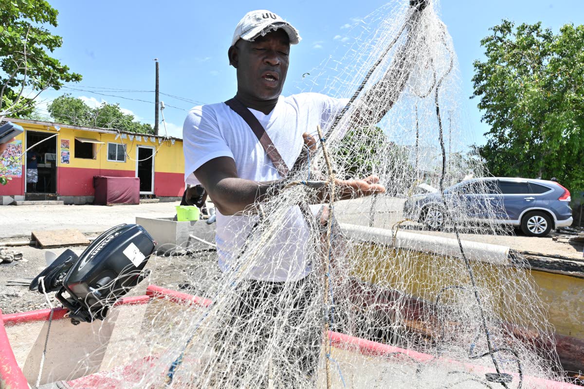 Inspecting his net at the Greenwich Town Fishing Village, Christopher Mahoney explains how the increasing oil prices impact his trade.