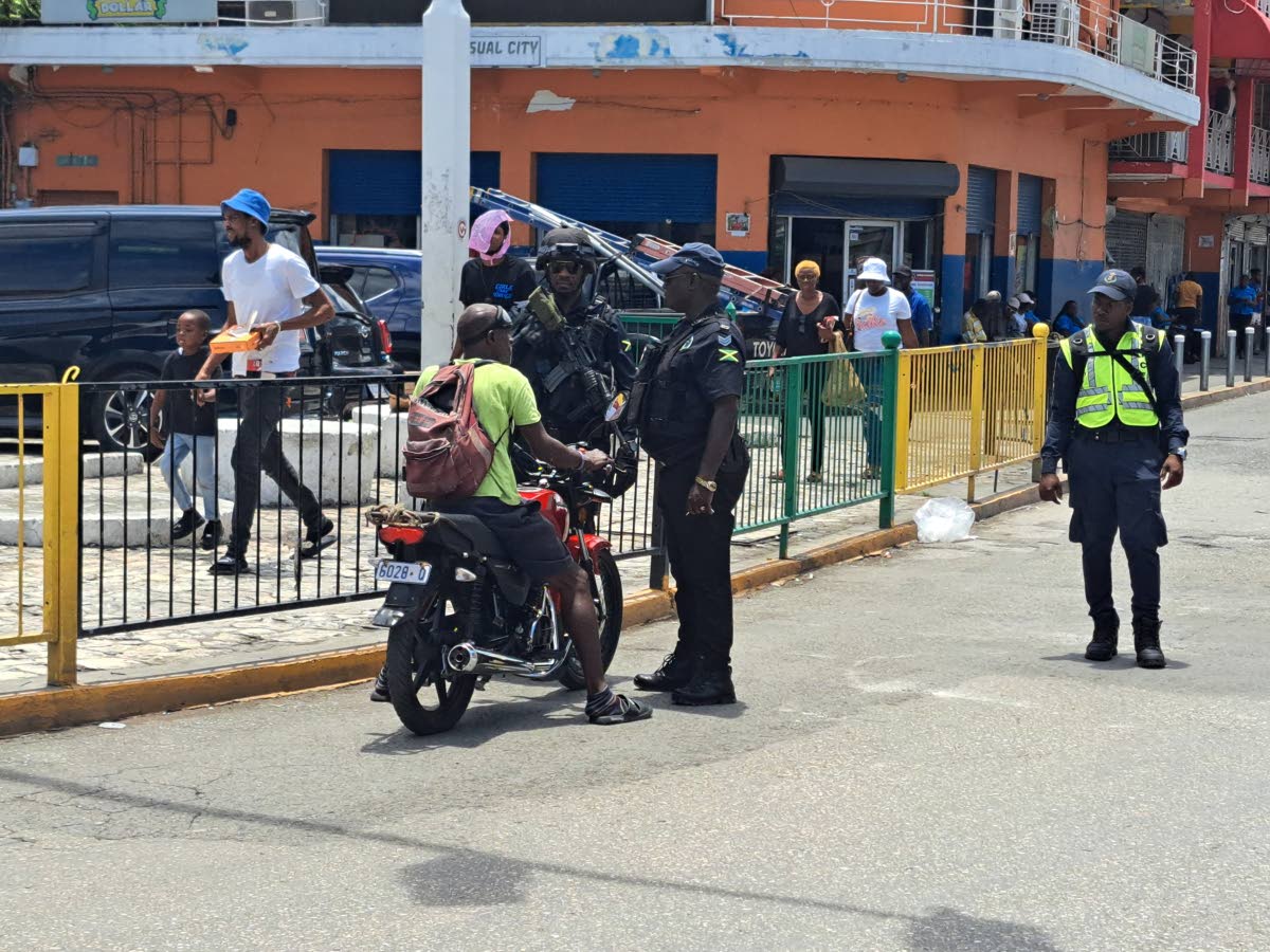 Officers from the St James Police Division stop a motorcyclist for breaching the Road Traffic Act by riding without a certified helmet in Sam Sharpe Square, Montego Bay, St James, yesterday. 
