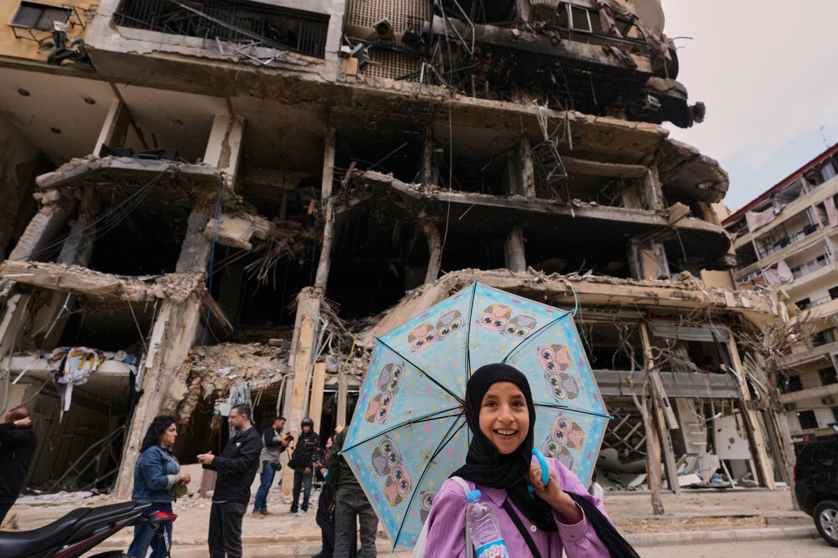 A girl passes in front of a destroyed building, following a ceasefire between Hezbollah and Israel in Dahiyeh, Beirut’s southern suburbs, Lebanon.
