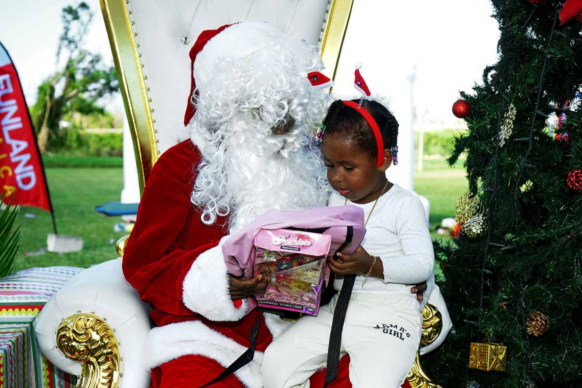 A child accepts a gift from Santa in this photo moment captured during an event at the William Knibb Memorial High School on Sunday, December 21, 2025. It was organised and hosted by FYI Consultancy Group in collaboration with the JN Foundation for residen