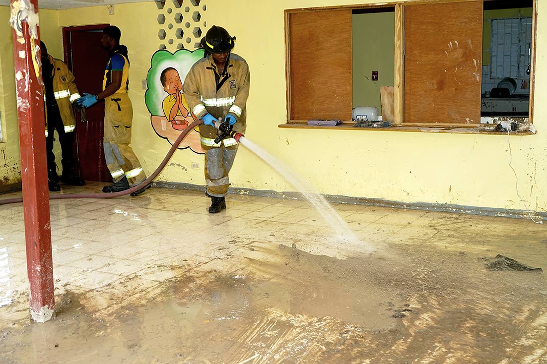 A member of the Jamaica Fire Brigade washes away mud and debris from a section of the Dudley Grant Demonstration Basic School in Catherine Hall, St James, during a workday organised by the JN Foundation in December 2025.