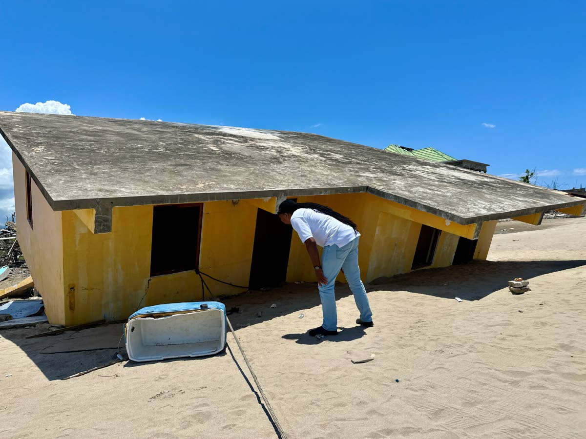 Basil Bennett peers into his house, which was uprooted  during the passage of Hurricane Melissa.