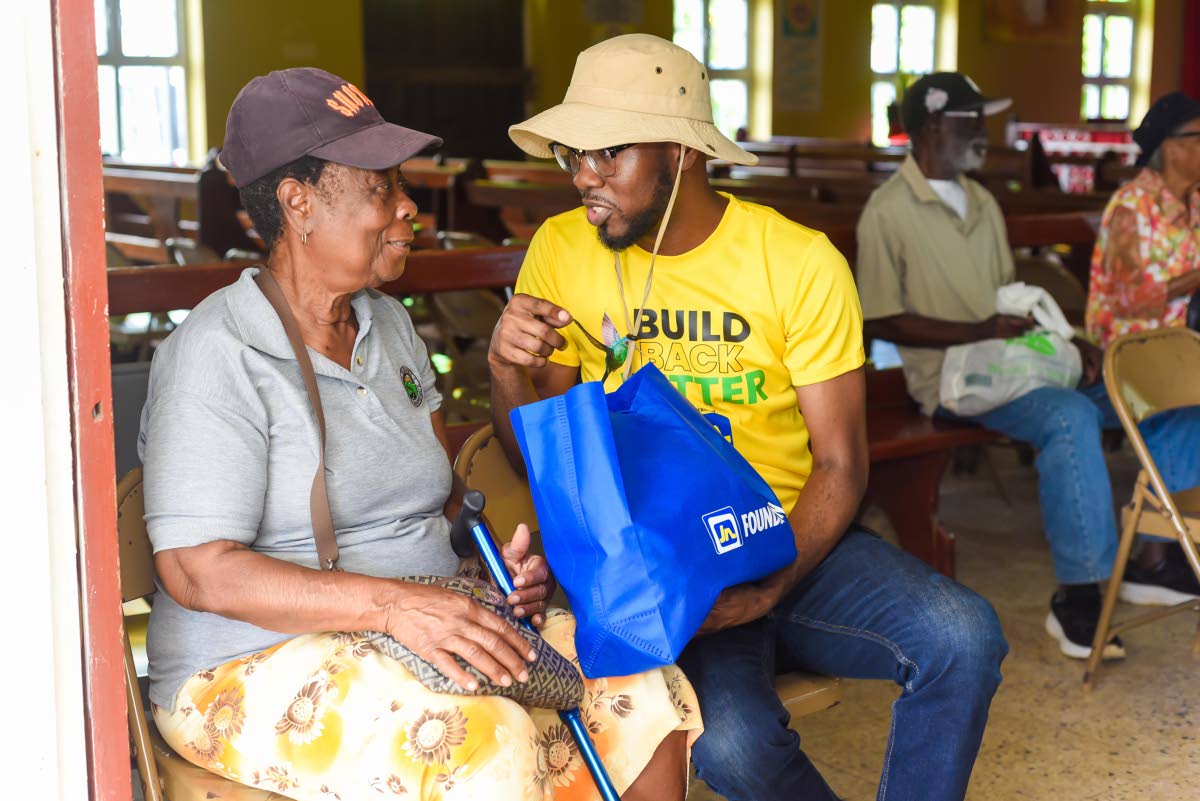 Omar Wright (right), lead for environment and community development programmes at the JN Foundation, assists Wakefield resident Mertelda Hemmings with a care package during the April 18 medical mission to the community which involved teams from the JN Foun