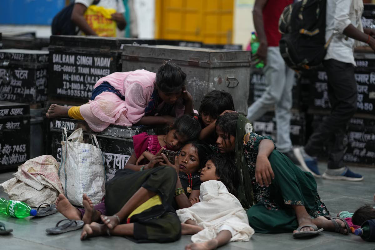 Children gather around a mobile phone as local residents rest at a railway station to escape the heat in Banda, northern Indian state of Uttar Pradesh, on Saturday, June 20.