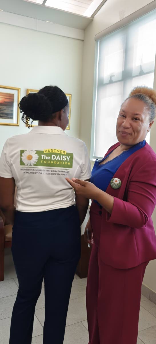 Dr Lisa Henry, director of nursing at Andrews Memorial Hospital, highlights The DAISY Award for Extraordinary Nurses polo shirt worn by Karlene Armstrong, coordinator of professional development and clinical excellence at AMH.