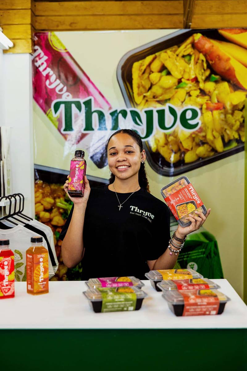 Kimberley Jones, ideator and creator of the Thryve Foods project, proudly poses with design mock-ups in hand at the Edna Manley School of Visual Arts exhibition for final-year students. 