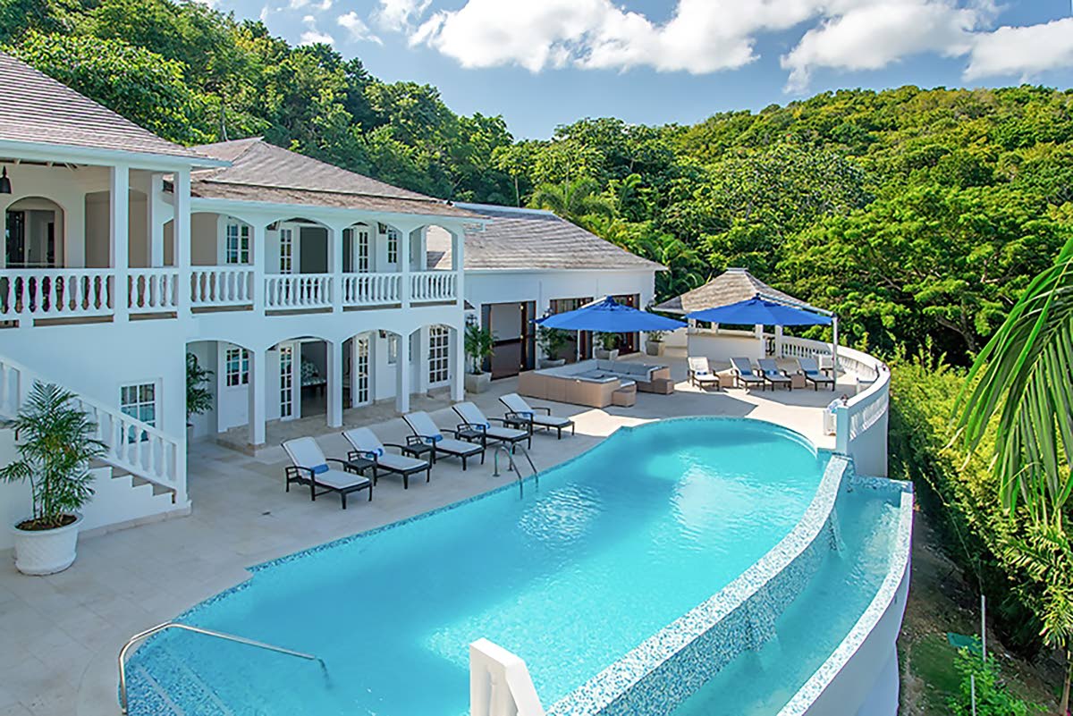 A 10-bedroom, 13-bathroom mansion set on a steep, heavily wooded hillside.										           