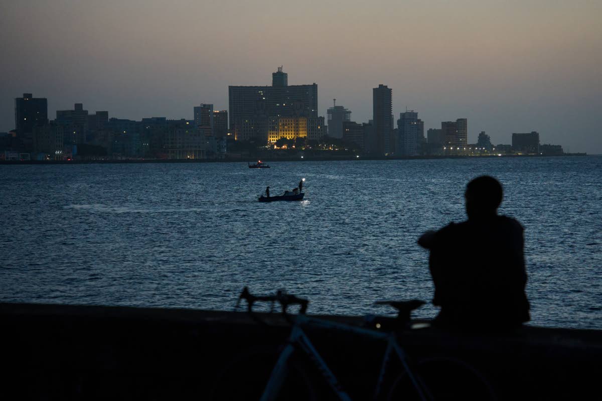 A man sits on the Malecón seawall after sunset during a blackout in Havana, Cuba, in July.