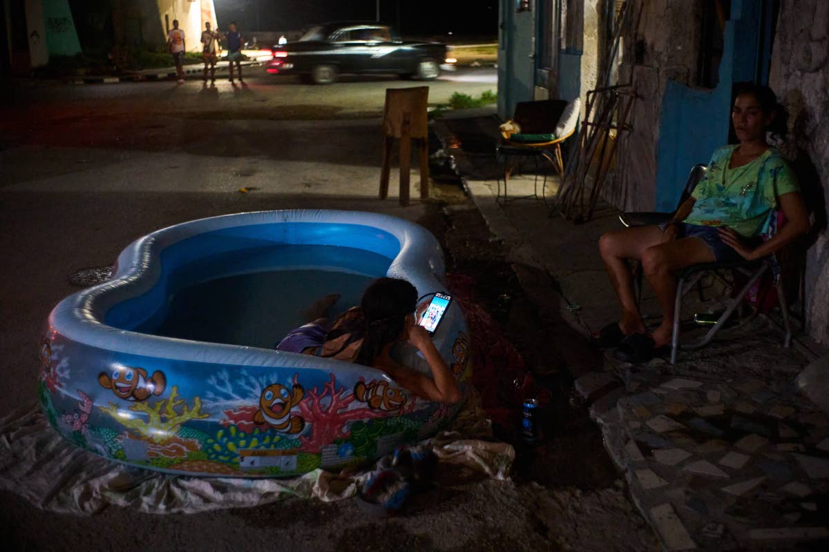A girl cools off in a plastic pool in the street in Havana, Cuba.
