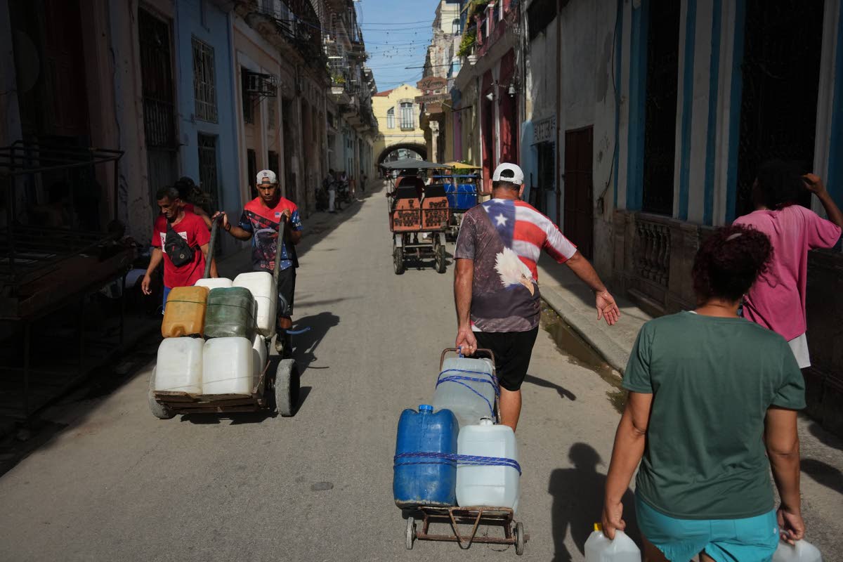 People carry water during a power outage in Havana, Cuba, in 2026.