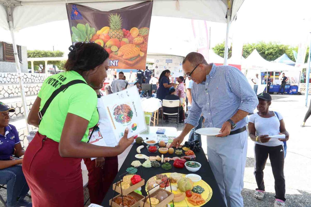 Dr Christopher Tufton, minister of health and wellness, stops by the Kingston Public Hospital Dietetics Department booth and engages with a member of the team during the hospital’s 250th Anniversary Health and Wellness Fair. 