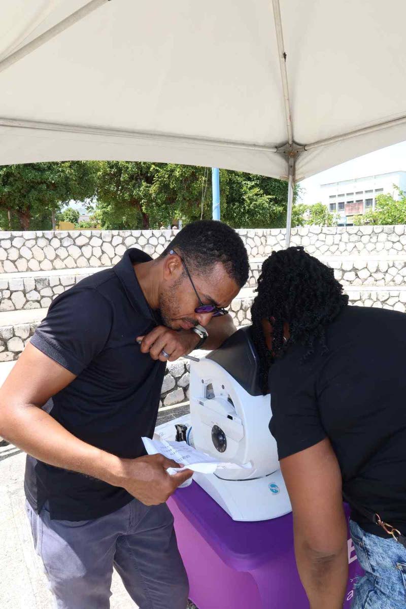 Carlington Willis, general manager of Eye Q Optical, provides a free eye examination as part of the vision screening services offered at the Kingston Public Hospital 250th Anniversary Health and Wellness Fair. 