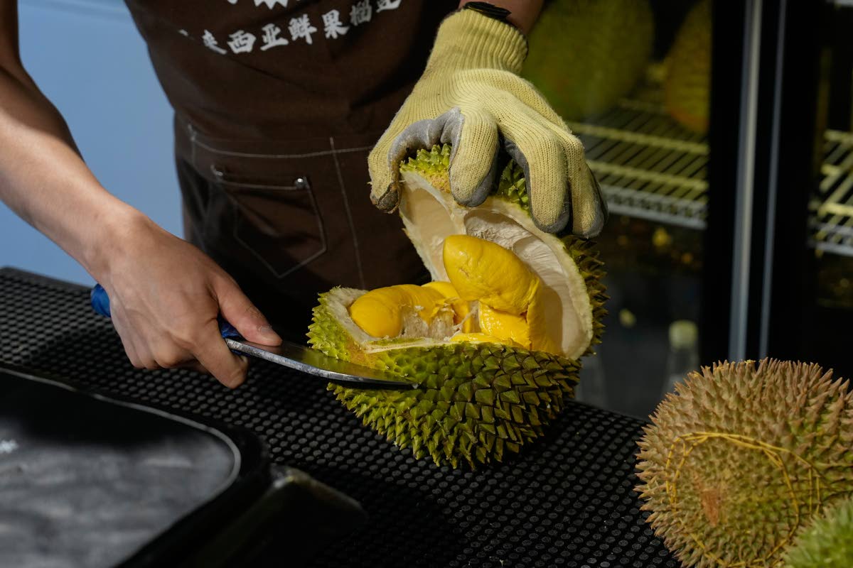 A worker opens durian fruits imported from Malaysia to pack and deliver for customers at a shop in Beijing, China.