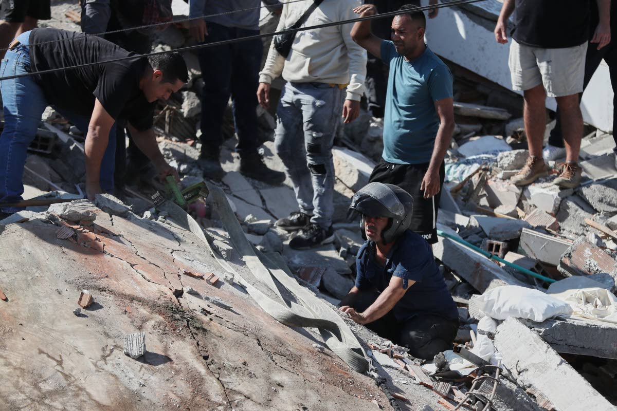 Residents and rescue workers search through the rubble of a collapsed building after an earthquake struck Cali, Colombia, Monday, Aug. 10, 2026. (AP Photo/Santiago Saldarriaga)
