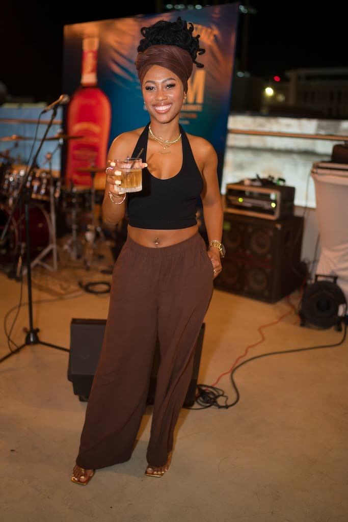 Trishana Williams, financial service representative, holds her Appleton Estate Spanish Sherry cocktail in hand, dressed in casual chocolate brown slacks, a matching head scarf, and a black halter.