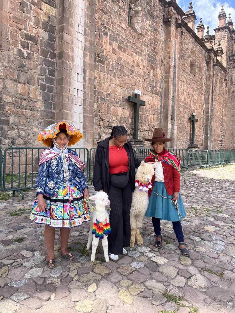 Shaneika Smith (centre) interacts with the locals and their alpacas in Cusco, Peru. 