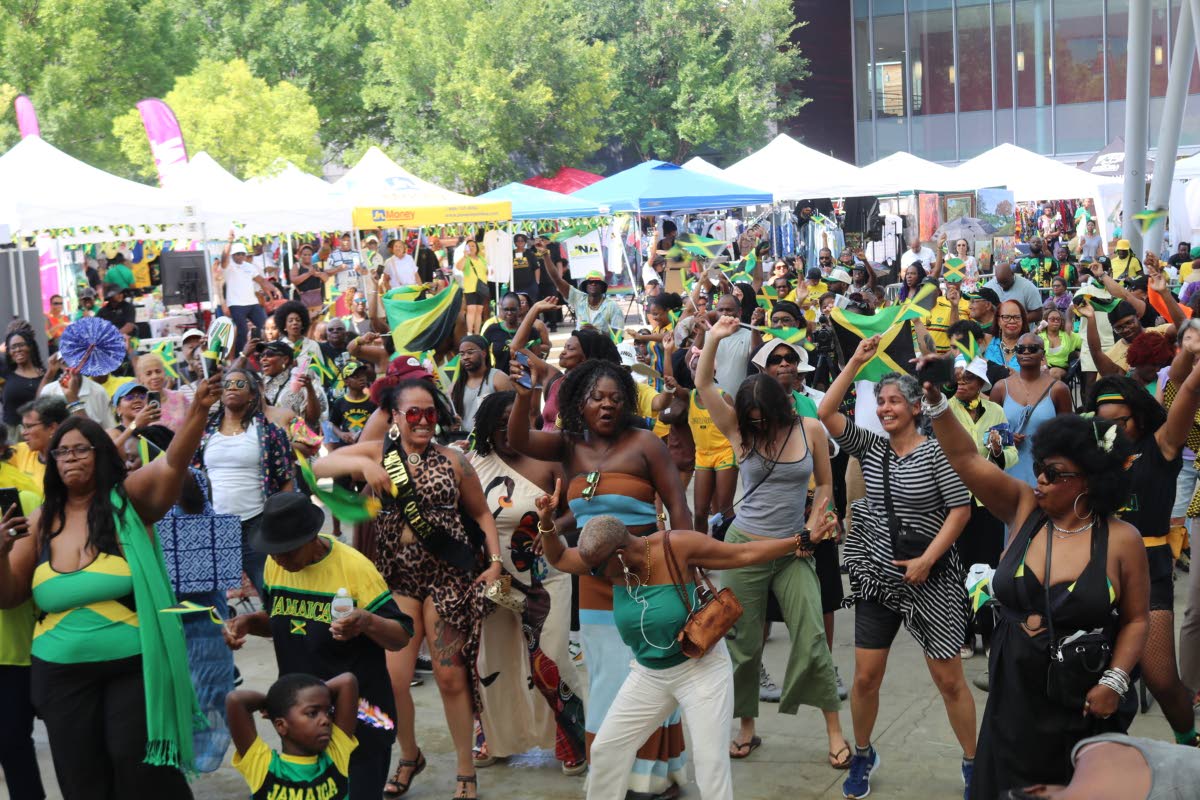 Patrons enjoy the vibrant atmosphere and reggae selections of DJ Najair as he takes them on a musical journey down memory lane during Jamaica Fest at Veterans Plaza in Silver Spring, Maryland, on Sunday, August 9.