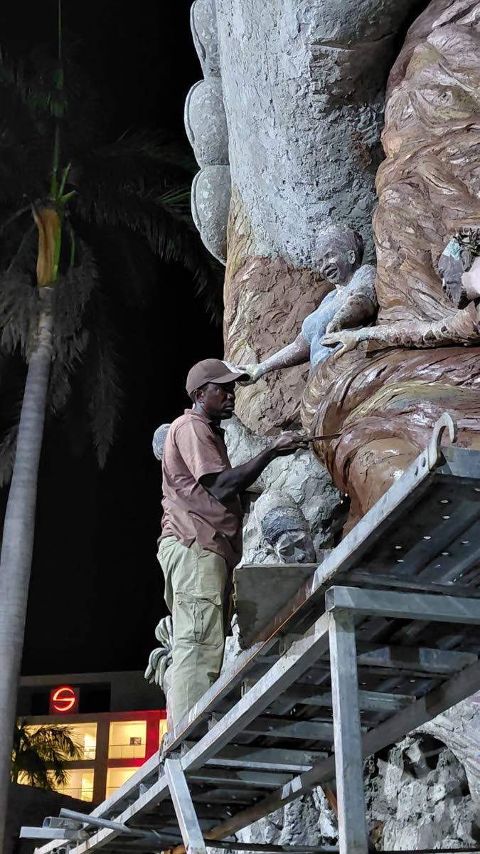 Sculptor Sheed Cole putting in the finishing touches on the 62-foot monument depicting the strength of the Jamaican people.