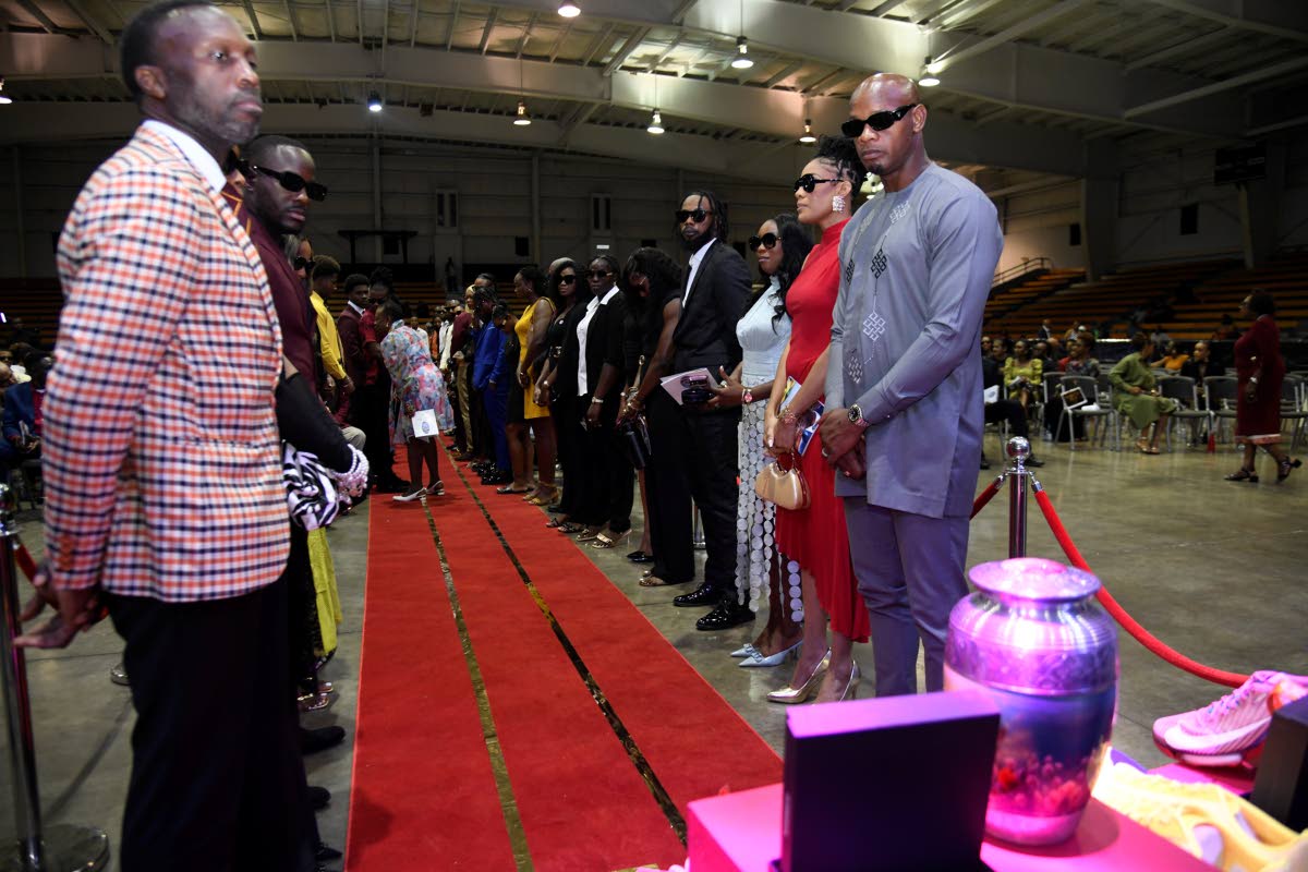Dr Neil Gardener (left), Olympian, and Asafa Powell, former 100m world record holder, form part of a guard of honour for the ashes of the late Stephen Francis during a Service of Thanksgiving at the National Indoor Sports Centre yesterday.  
