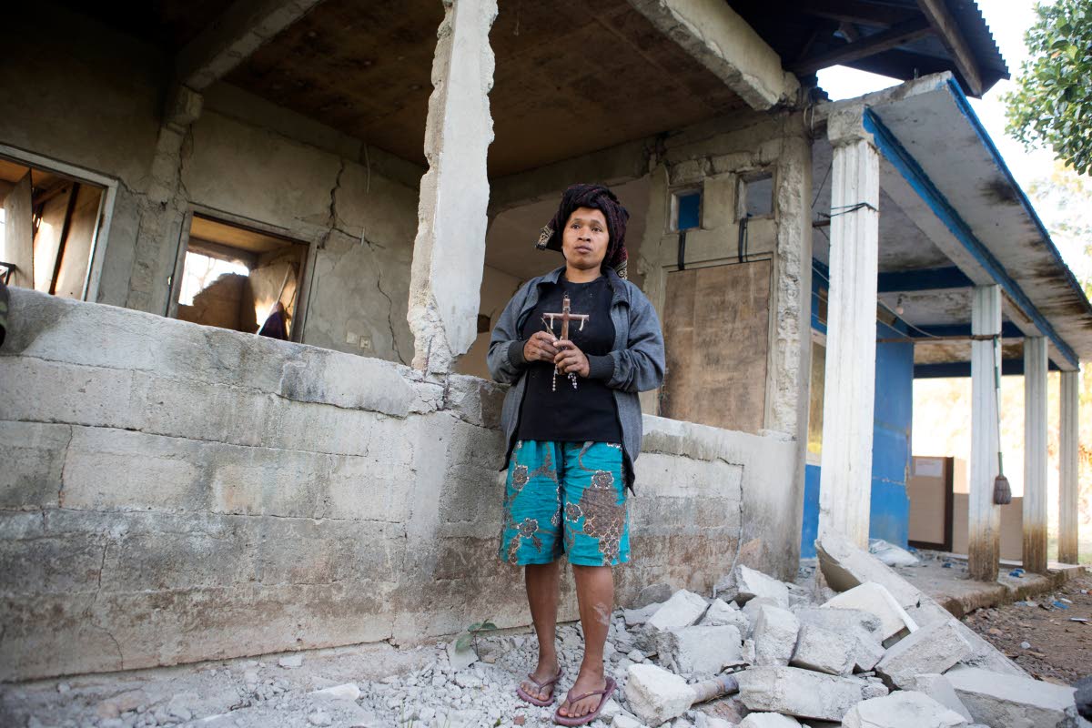 A woman holds a cross she recovered from the rubble of her earthquake-damaged house in Mbeliling, East Nusa Tenggara province, Indonesia, Sunday, Aug. 16, 2026. (AP Photo/Firdia Lisnawati)