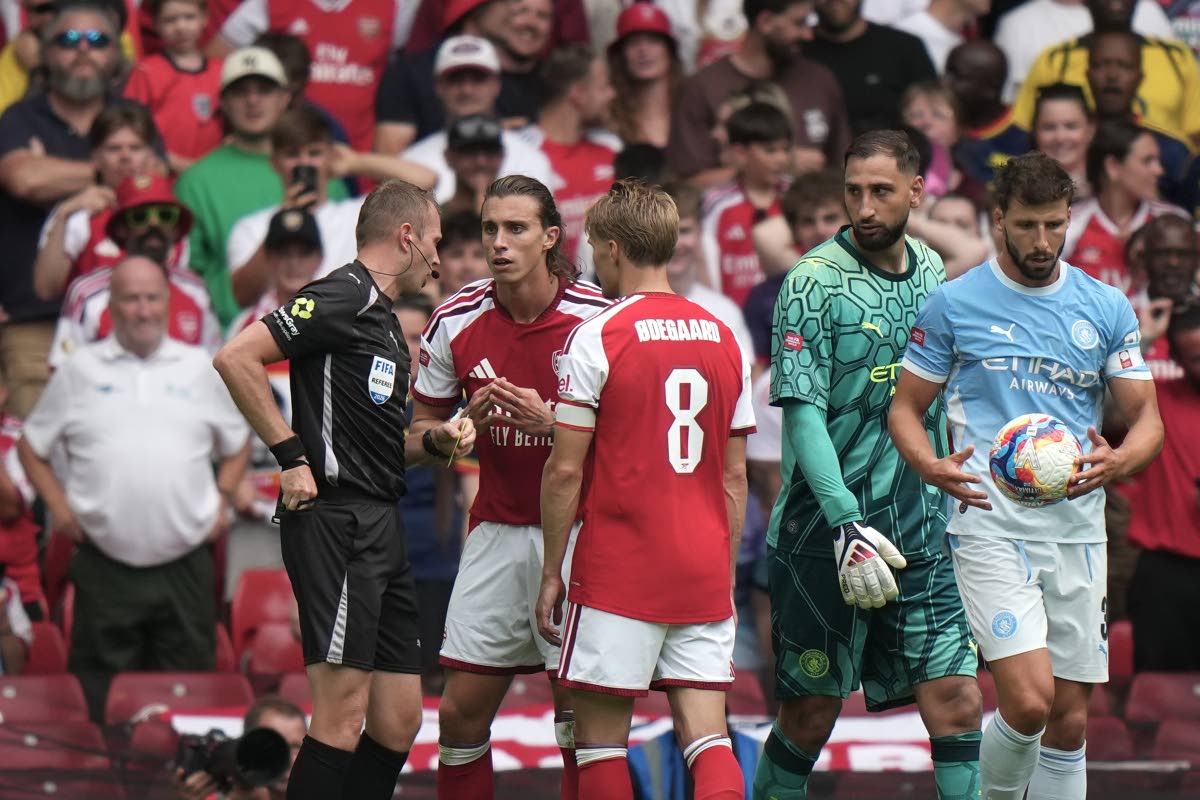 Referee Sam Barrott, left, discusses with Arsenal's Riccardo Calafiori, second left, during the FA Community Shield final soccer match between Arsenal and Manchester City in Cardiff, Wales, Sunday, Aug.16, 2026. (AP Photo/Alastair Grant)