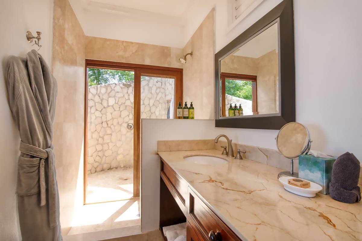 A granite-finished bathroom with indoor-outdoor rain showers. 