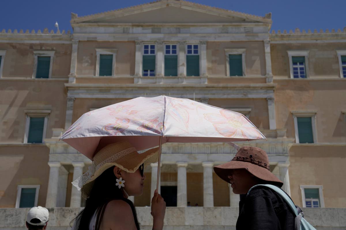 Tourists wearing hats visit the Tomb of the Unknown Soldier outside the Greek Parliament in Athens, Greece.