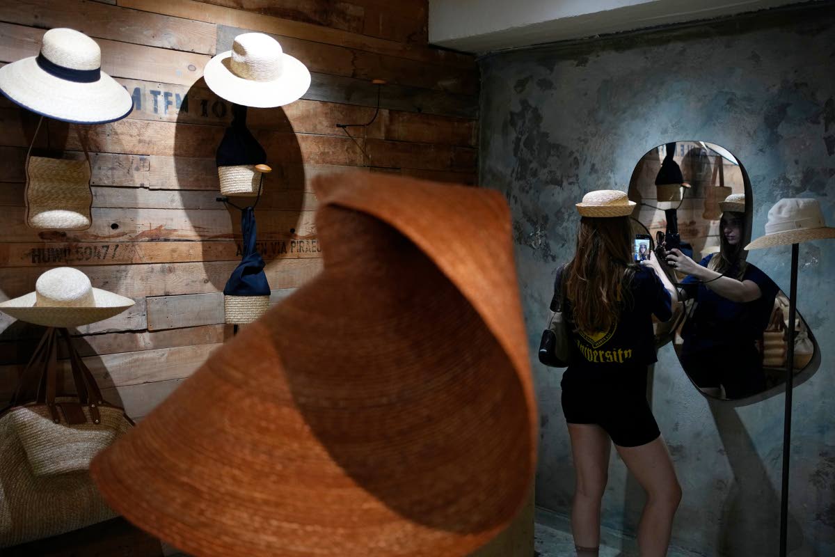 A Russian tourist tries on a hat and takes a selfie at a shop in Athens, Greece.