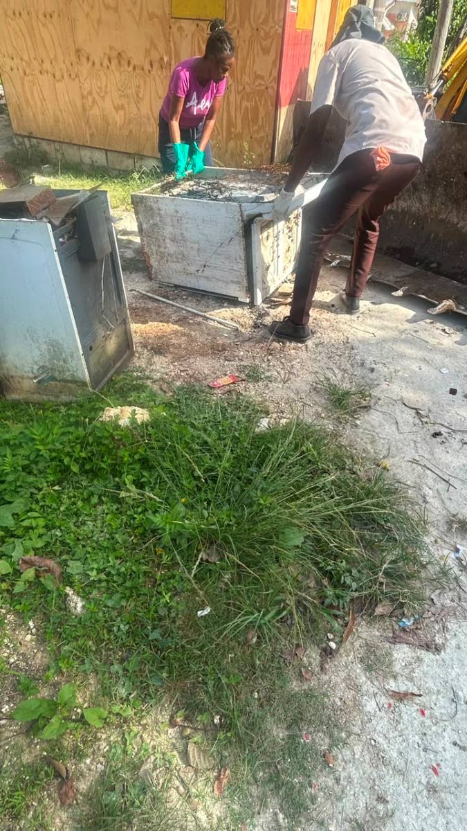 Public Health Inspector Intern Jonathan McLean and Strathbogie Lane resident and committee member lift an old stove during a community cleanup exercise in the Westmoreland community.
