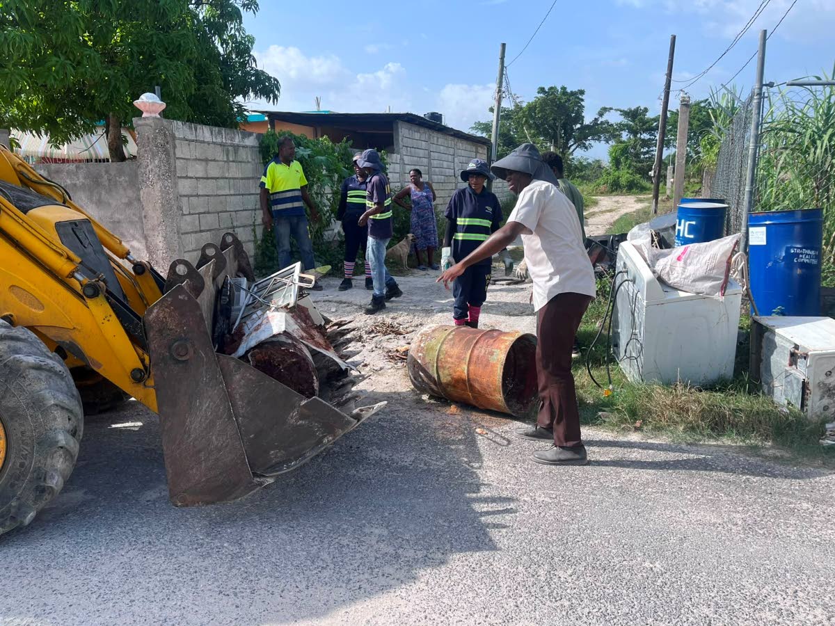 Public Health Inspector Intern Jonathan McLean helps residents remove bulky waste from Strathbogie Lane in Savanna-la-Mar, Westmoreland, as part of a community cleanup initiative.