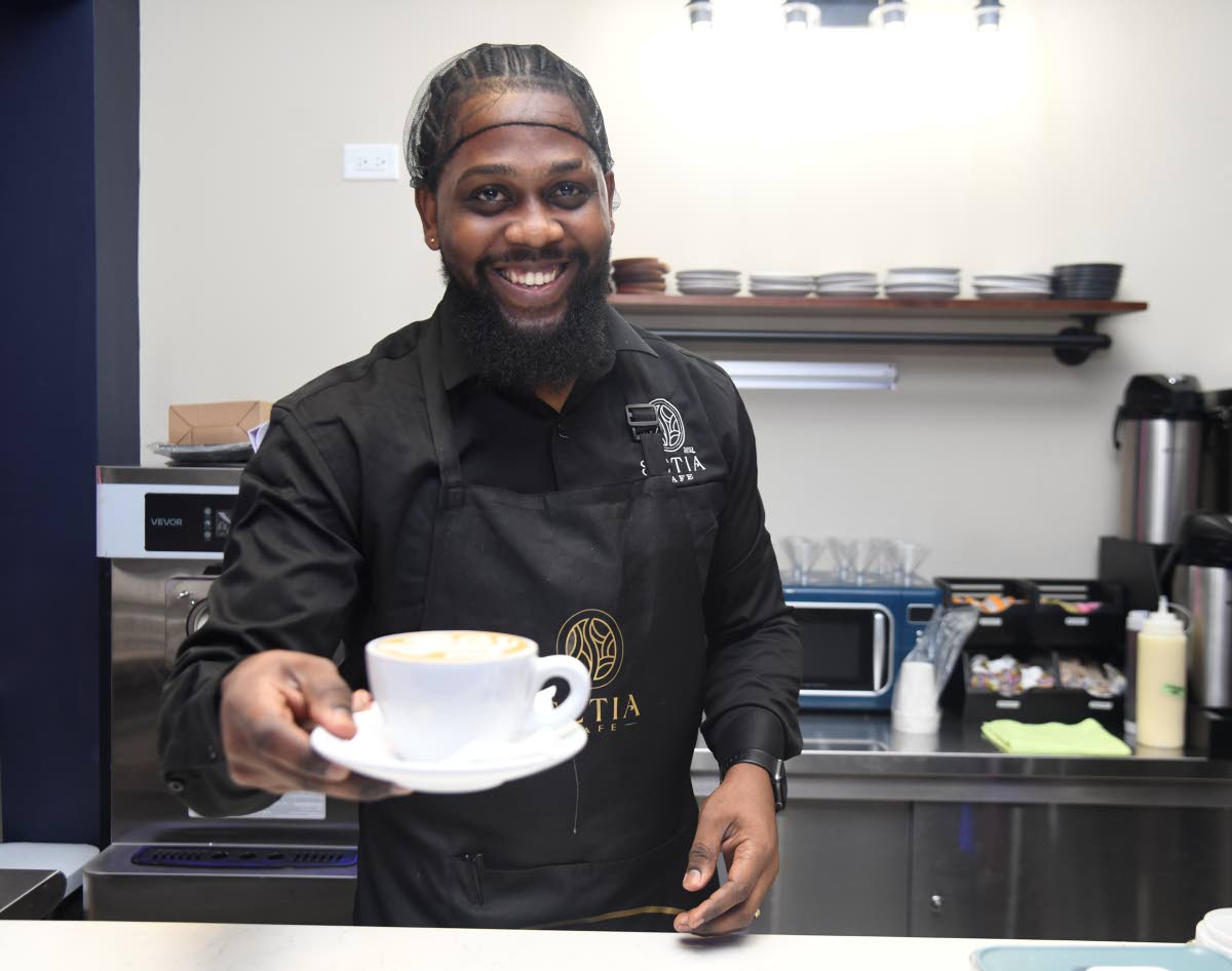 Ricardo Jackson, Setia’s master barista, sports a radiant smile as he serves a fresh cappuccino.