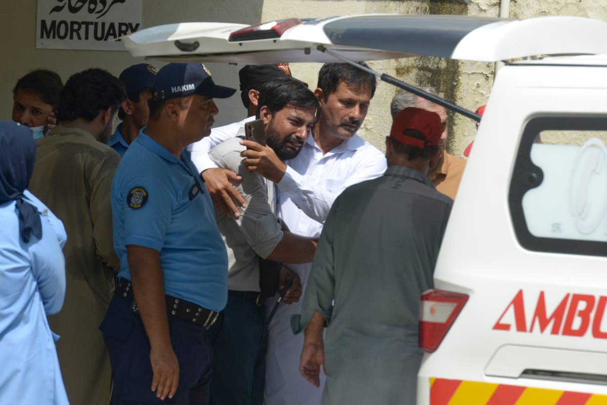 A father of a victim in a fire is comforted as his child's coffin is carried outside a hospital in Islamabad, Pakistan.