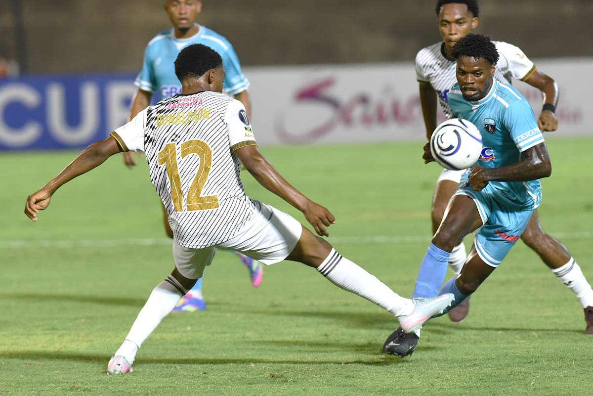 Jairo Alegria (right) from Sacedo FC, skips a tackle from Livingstone Donaldson (left) from Cavalier during their Concacaf Caribbean Cup football match at the National Stadium on August 20.