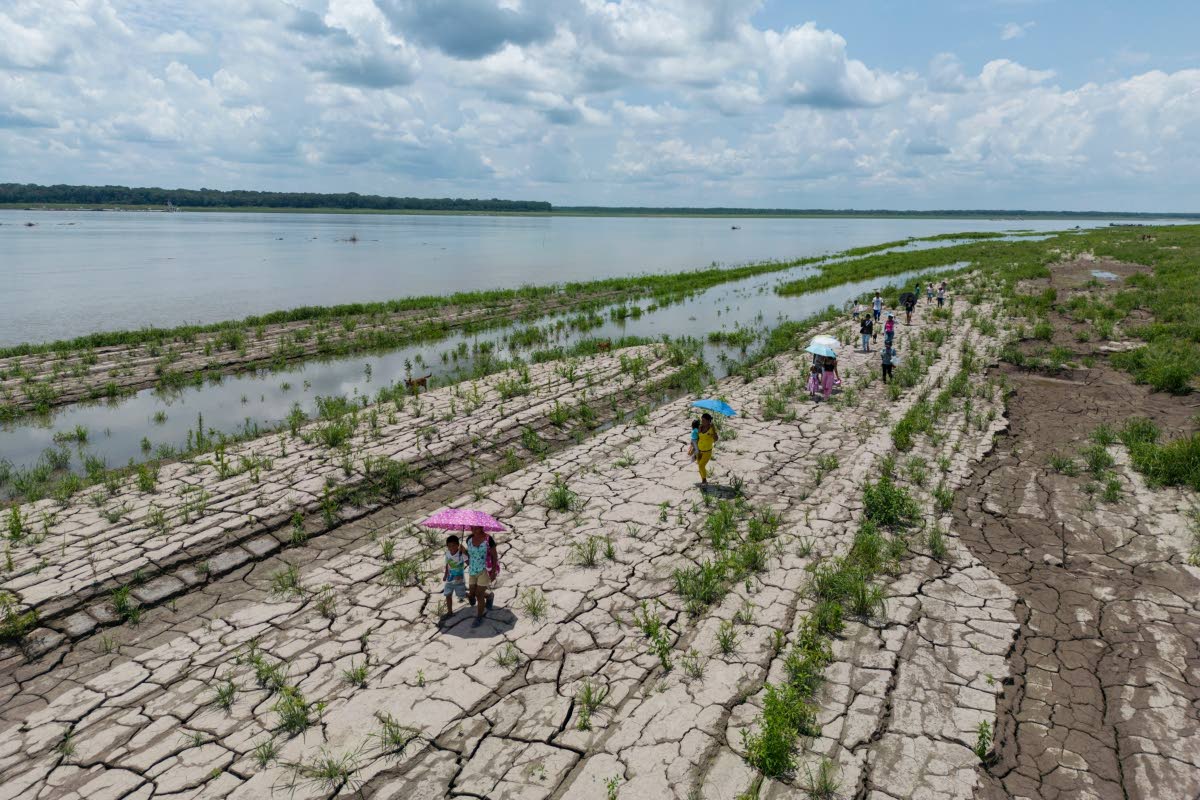 People walk through a part of the Amazon River that shows signs of drought in Santa Sofia, on the outskirts of Leticia, Colombia, in October 2024. 