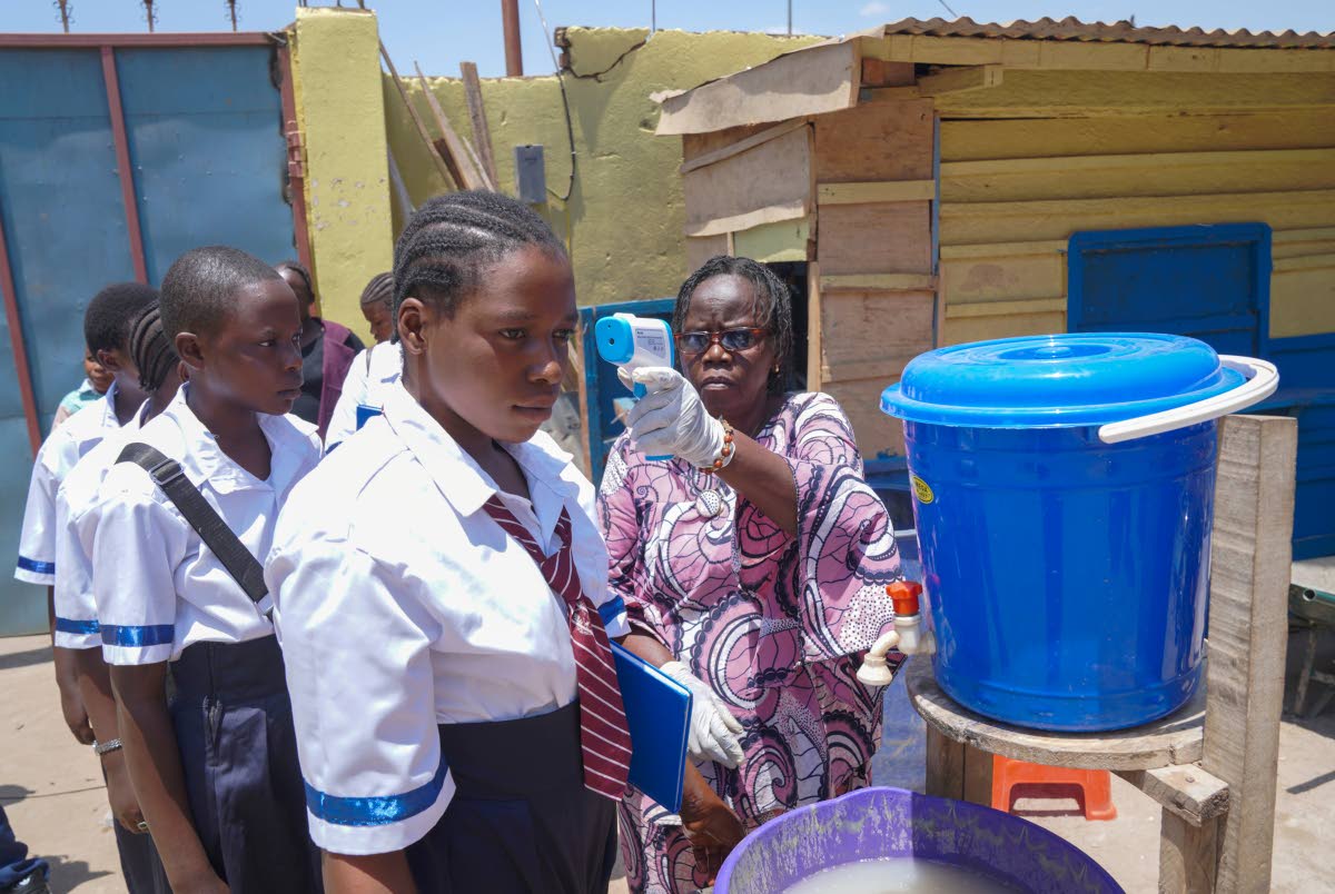 A school official checks students' temperatures as they enter school, on the first day of the new school year amid the Ebola virus outbreak, in Ituri, Congo, Tuesday, Sept.1, 2026. (AP Photo/Dieudonne Dirole)