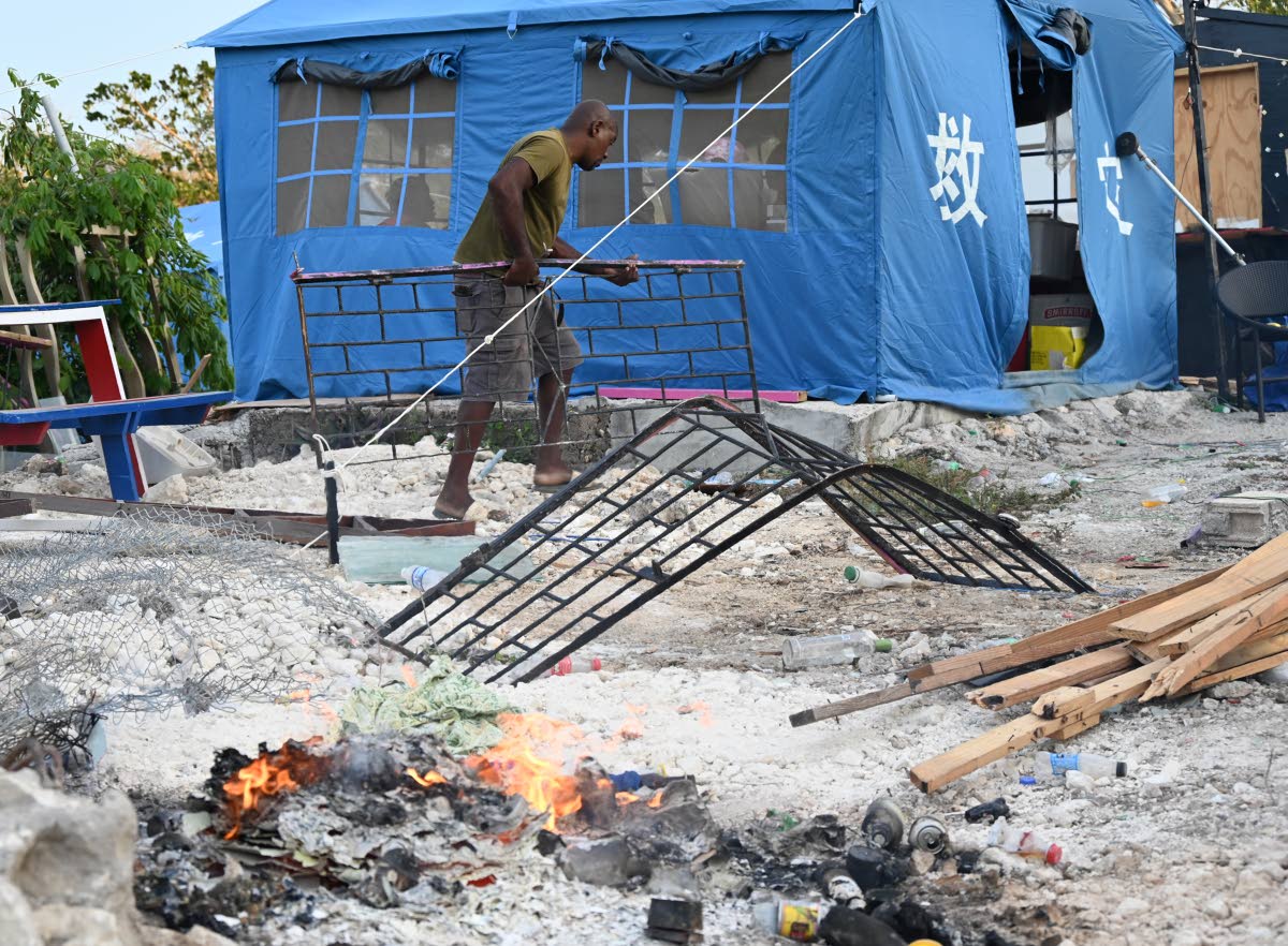 In this August 20 photo, a man is seen removing items Coopers Pen, Trelawny, after 20 houses had been demolished. Another approximately 40 households now fear that the crew may return.