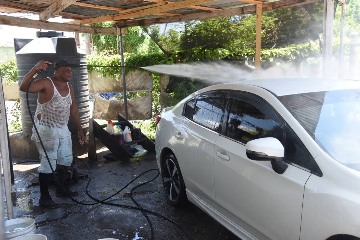 Michael Barnett washes a car with water from one of his tanks at his Kingston Gardens Public Car Wash in central Kingston on Tuesday.