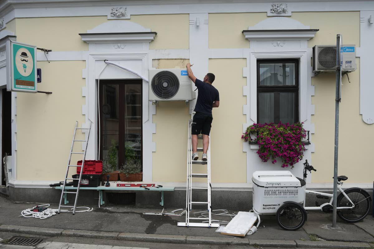 A worker installs a new air conditioning unit during a hot summer day in Belgrade, Serbia, June 30.