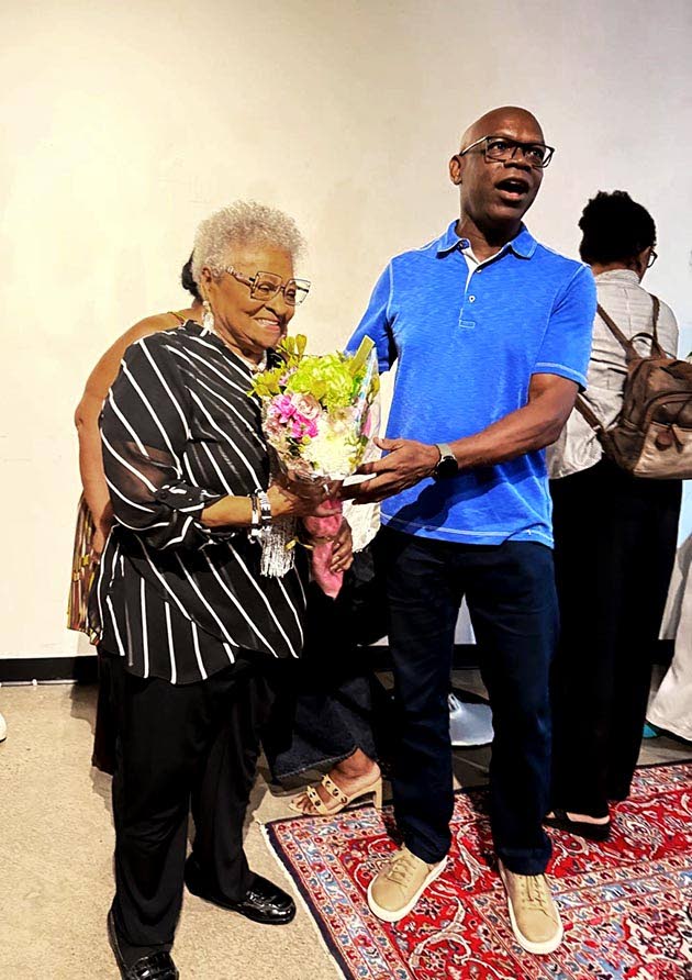 Jamaica-born O. Dane Lawrence presents flowers to retired educator Florence Harrison during the launch of a tribute book celebrating her influence on former students.